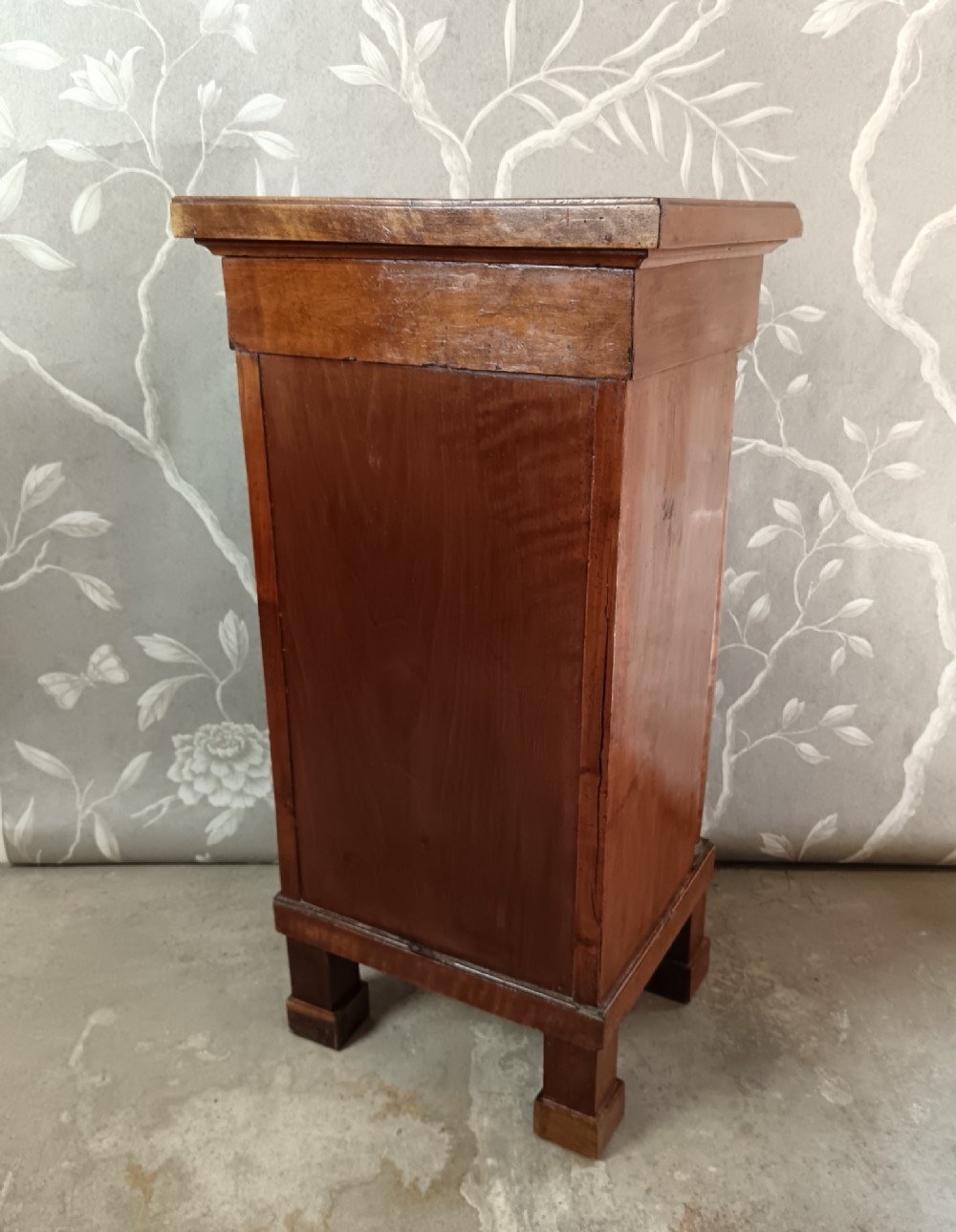 A nineteenth-century Italian Empire walnut bedside cabinet featuring a top drawer, single panelled door, brass rosette mounts, and flanking column columns. View X