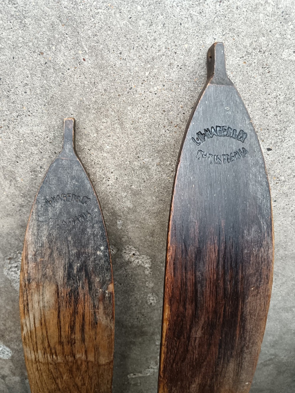 A pair of dark wood turn-of-the-century Norwegian skis accompanied by bamboo ski poles with leather bindings and cane baskets. View II