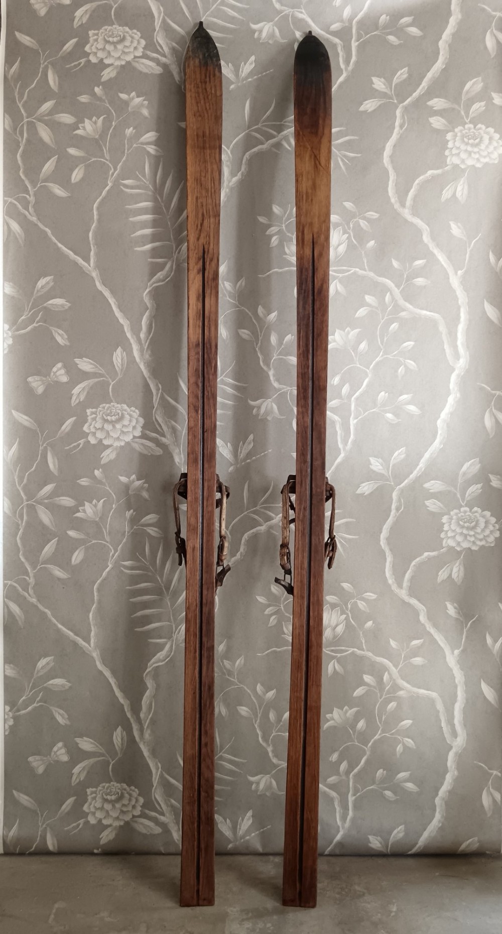 A pair of dark wood turn-of-the-century Norwegian skis accompanied by bamboo ski poles with leather bindings and cane baskets. View III