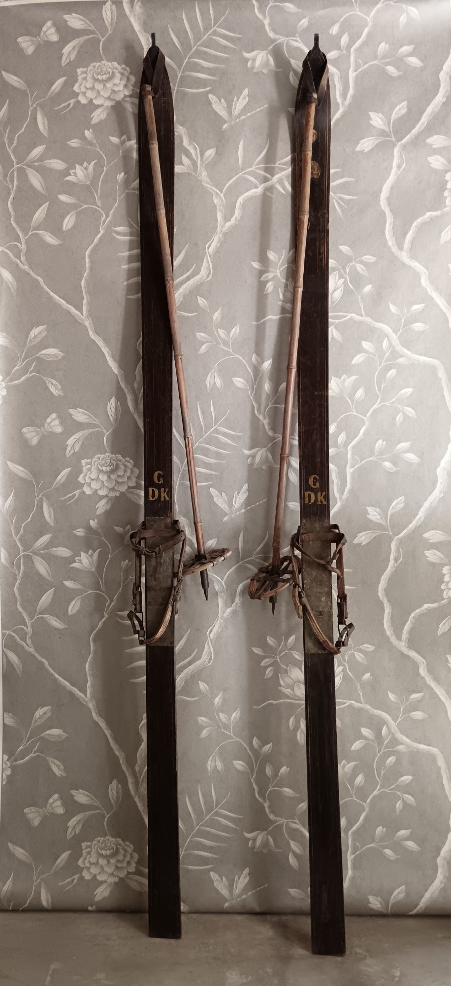 A pair of dark wood turn-of-the-century Norwegian skis accompanied by bamboo ski poles with leather bindings and cane baskets. View IV