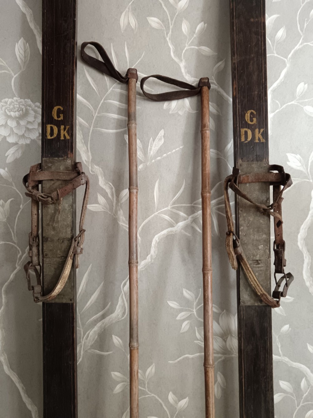 A pair of dark wood turn-of-the-century Norwegian skis accompanied by bamboo ski poles with leather bindings and cane baskets. View V