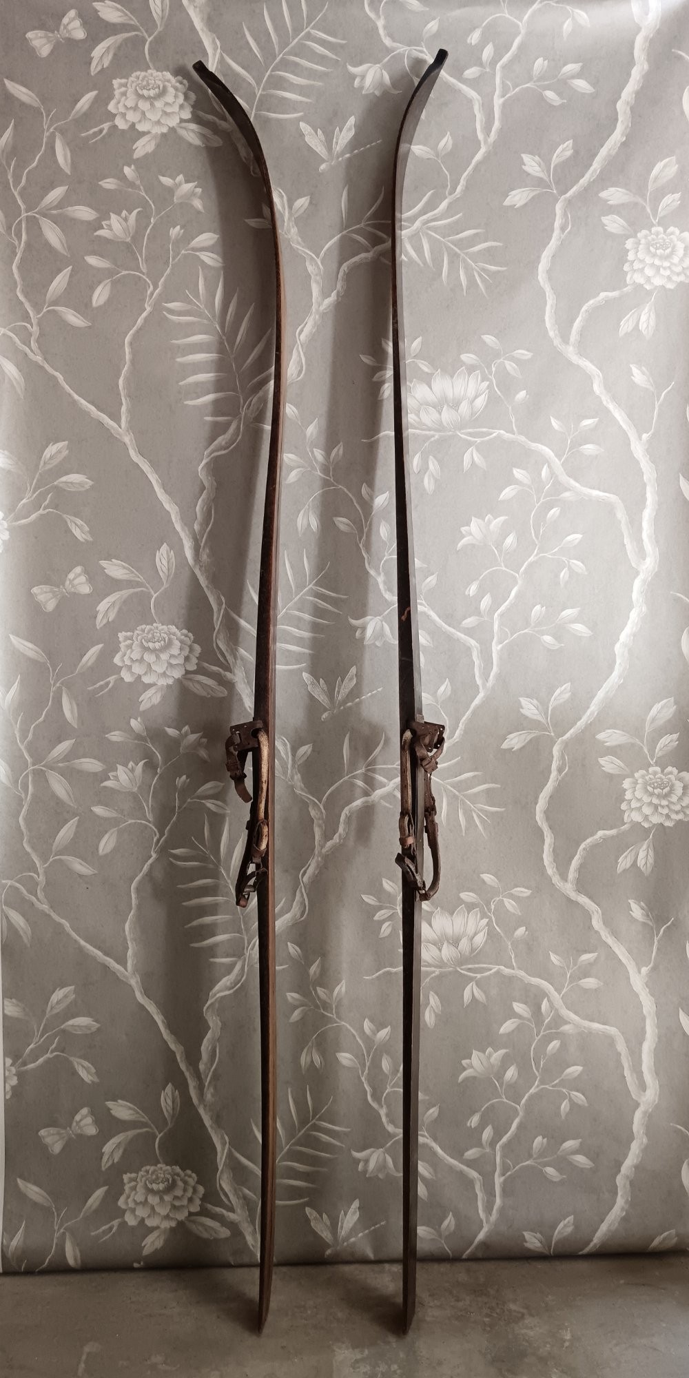 A pair of dark wood turn-of-the-century Norwegian skis accompanied by bamboo ski poles with leather bindings and cane baskets. View VI