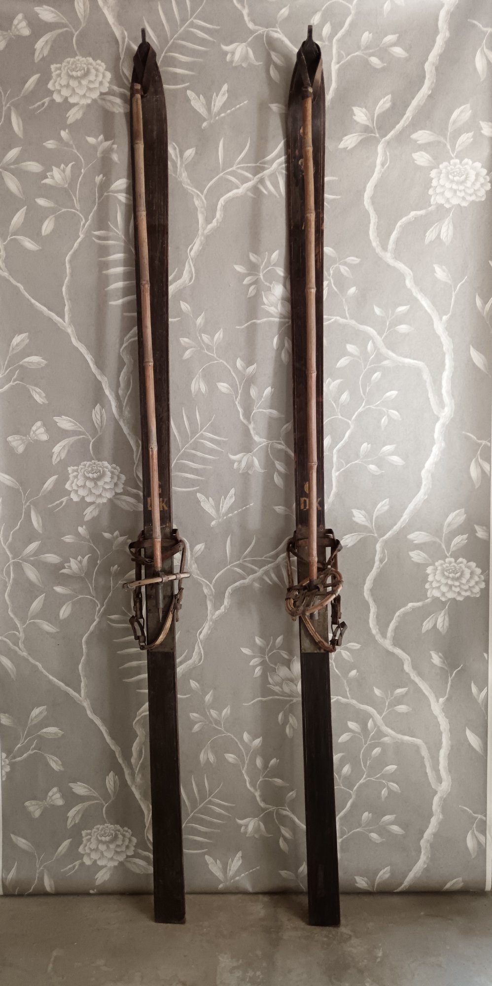 A pair of dark wood turn-of-the-century Norwegian skis accompanied by bamboo ski poles with leather bindings and cane baskets. View VII