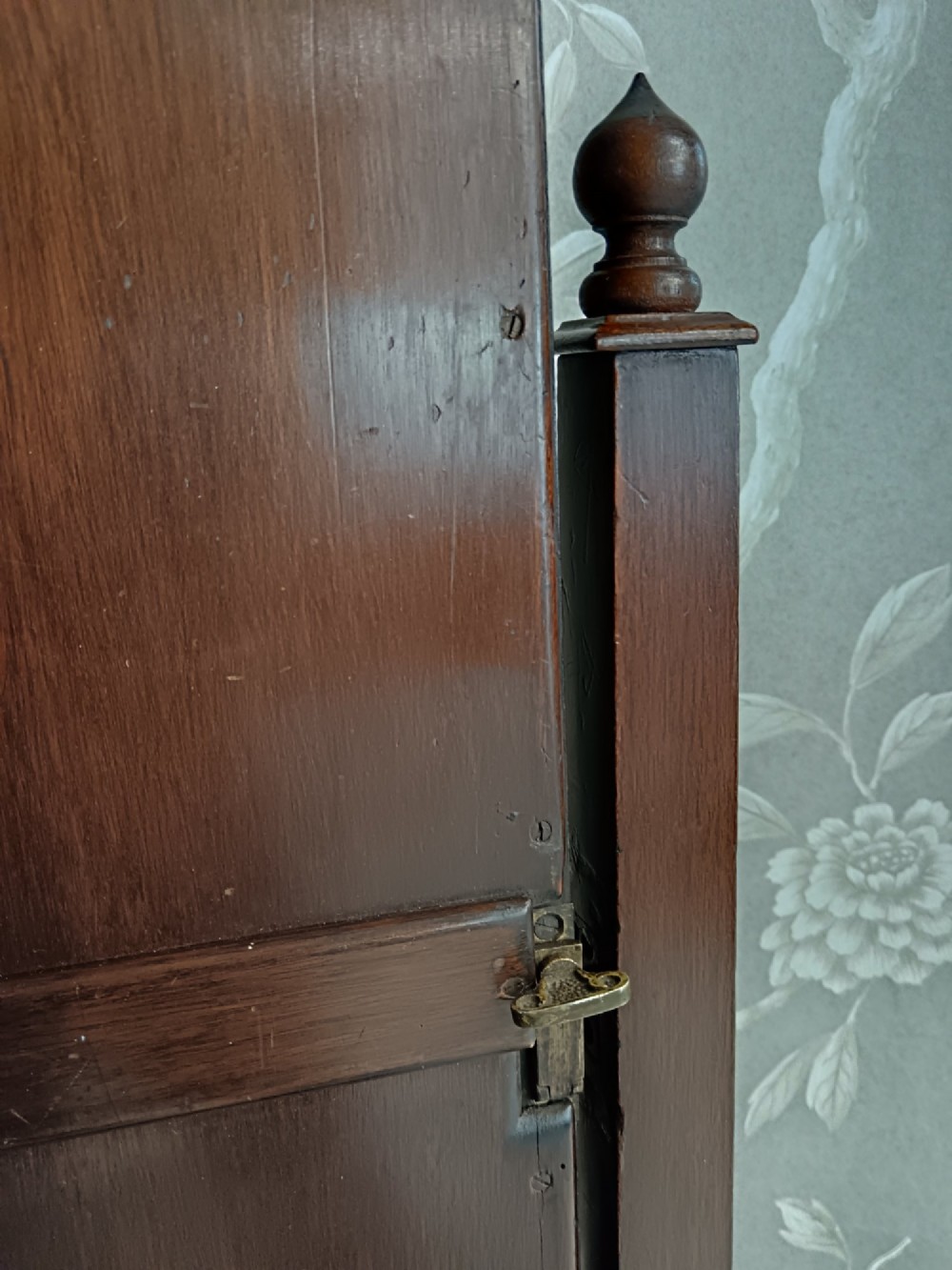 A late Victorian mahogany cheval mirror featuring a rectangular full-length pivoting frame set between turned finial posts on a shelf base with brass castors. View VIII