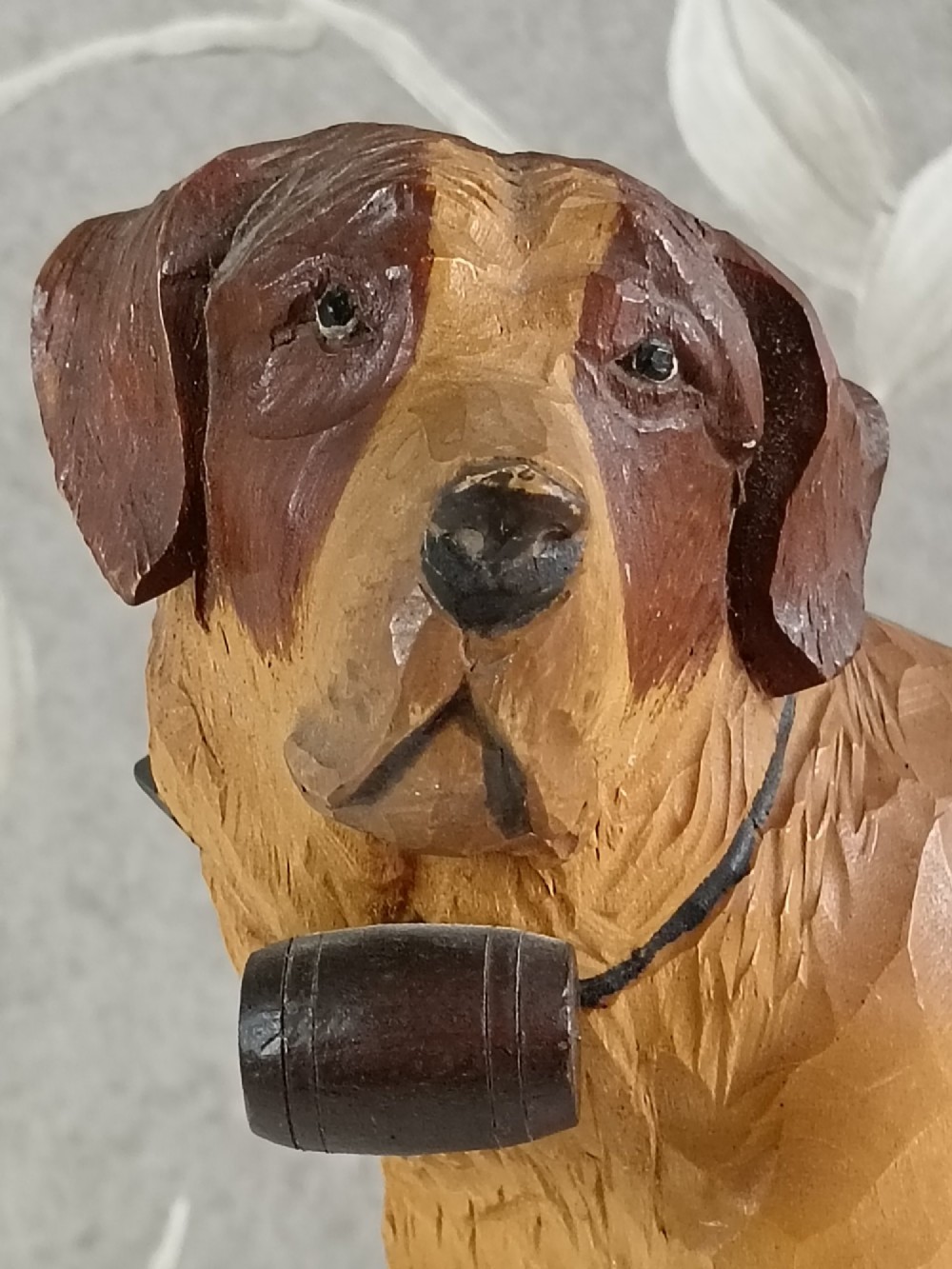A carved and painted wooden sculpture of a standing Saint Bernard dog wearing a barrel around its neck. View II