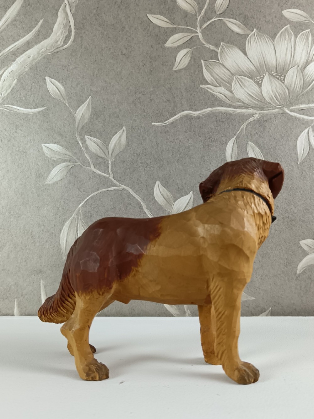 A carved and painted wooden sculpture of a standing Saint Bernard dog wearing a barrel around its neck. View III