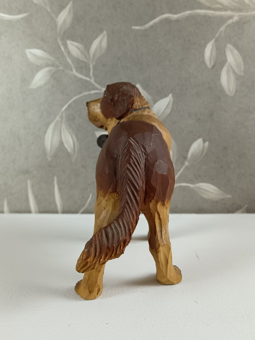 A carved and painted wooden sculpture of a standing Saint Bernard dog wearing a barrel around its neck. View IV