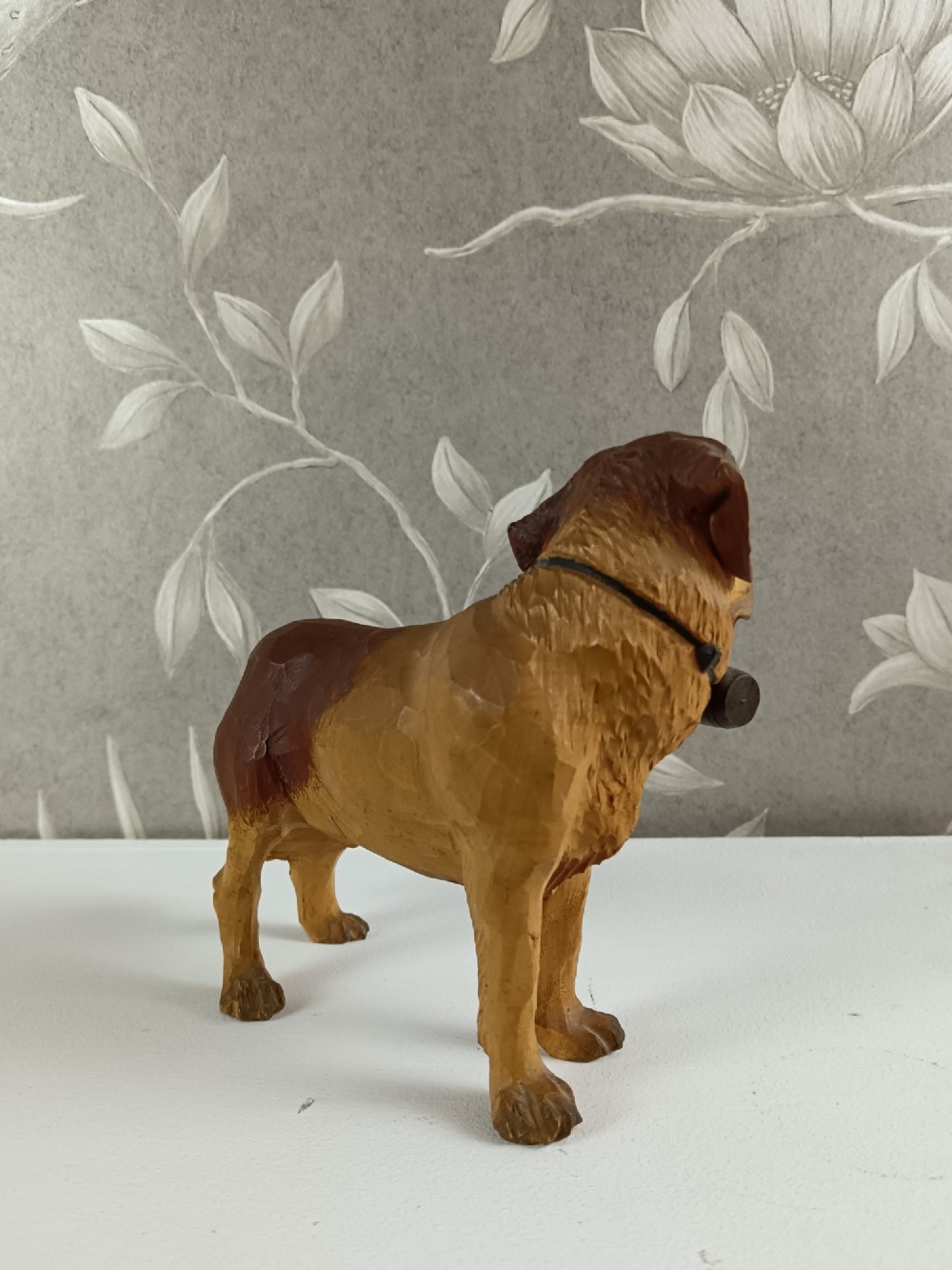 A carved and painted wooden sculpture of a standing Saint Bernard dog wearing a barrel around its neck. View X