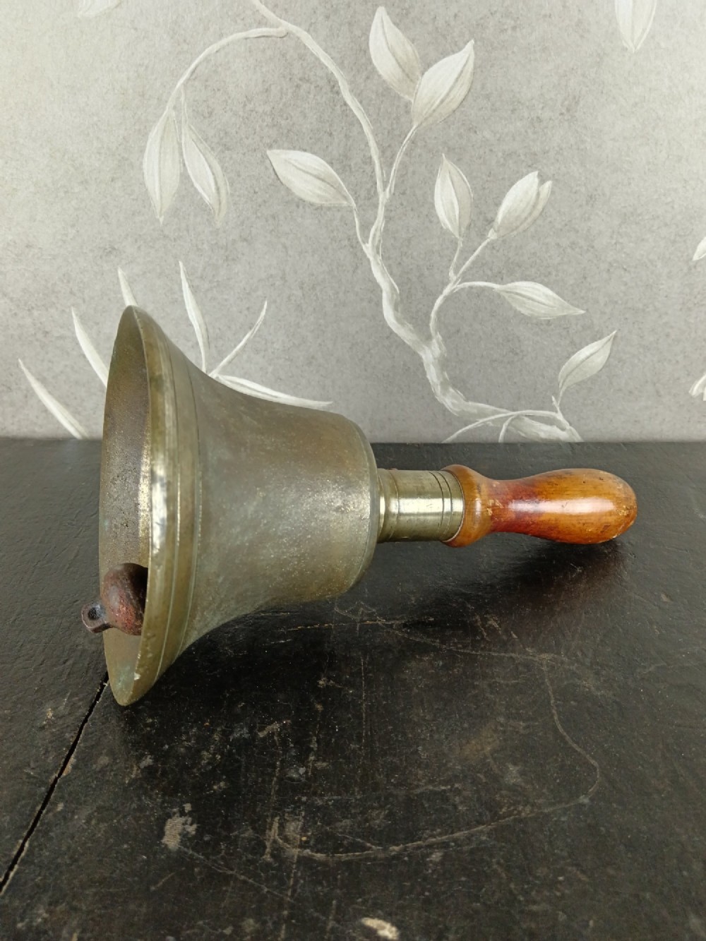 A cast brass military handbell featuring an engraved broad arrow mark and a turned dark wood handle. View IV