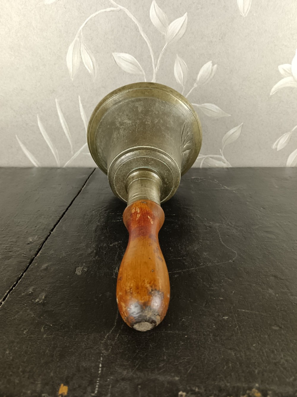 A cast brass military handbell featuring an engraved broad arrow mark and a turned dark wood handle. View VI