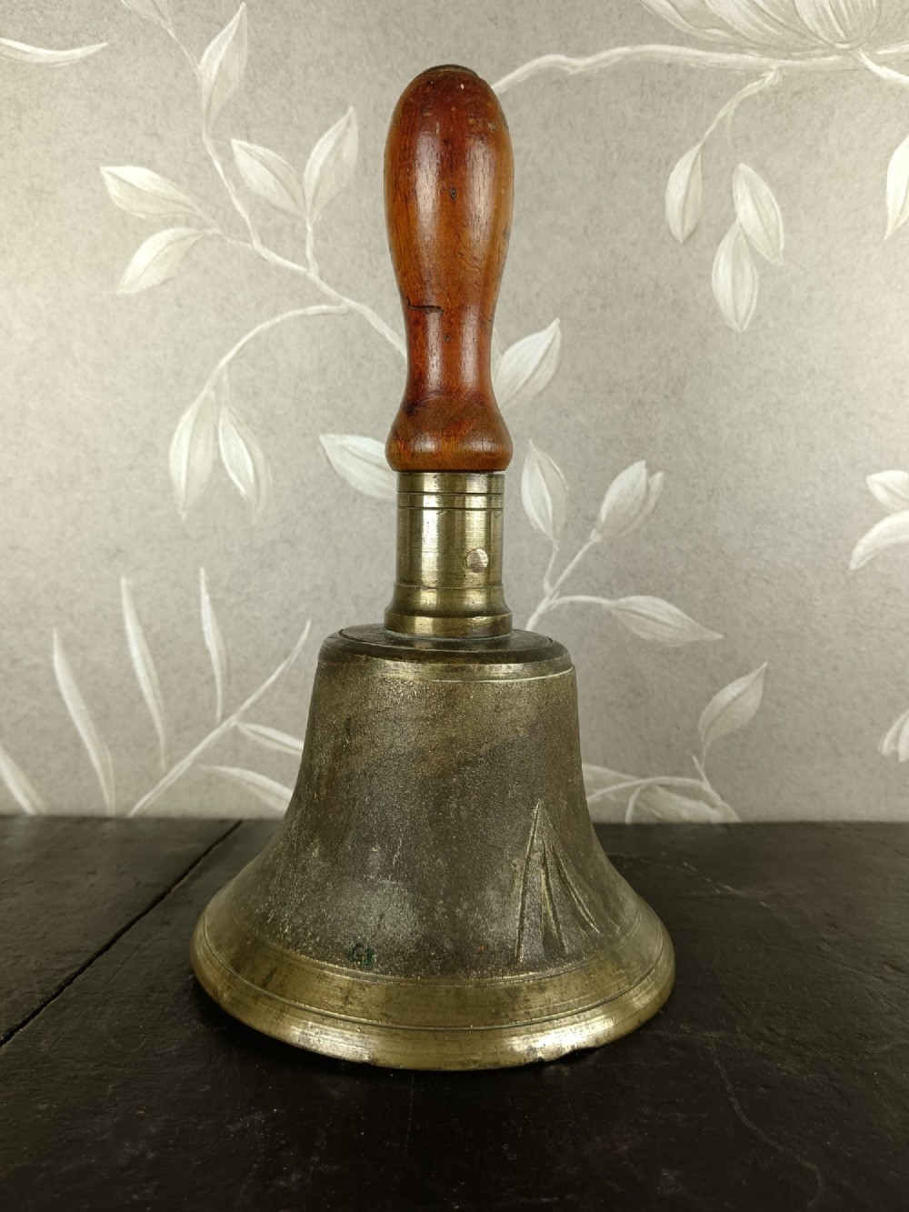 A cast brass military handbell featuring an engraved broad arrow mark and a turned dark wood handle. View VII