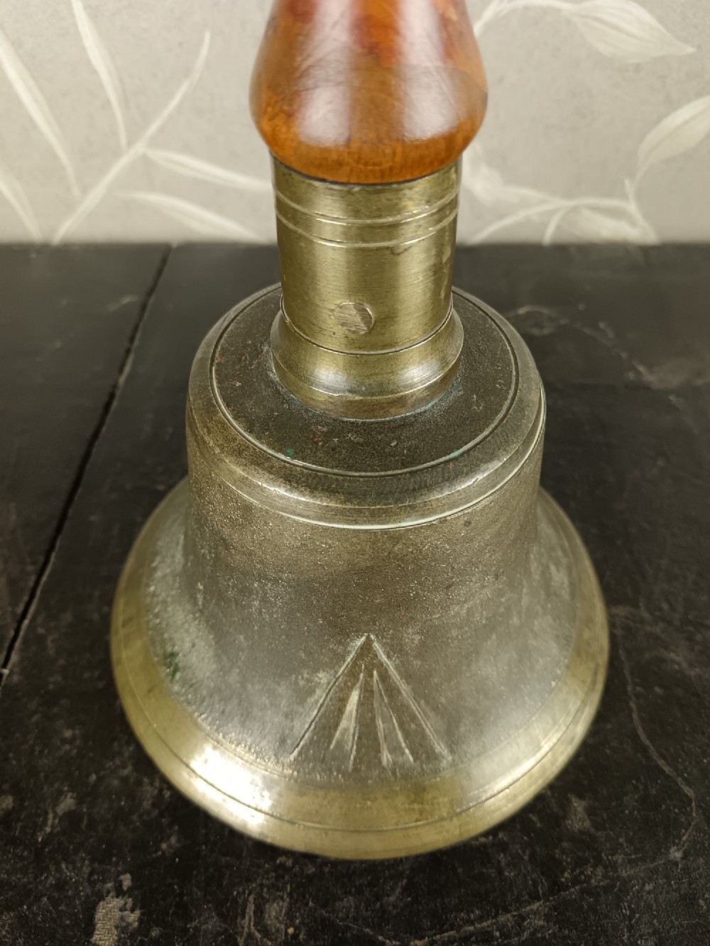 A cast brass military handbell featuring an engraved broad arrow mark and a turned dark wood handle. View VIII