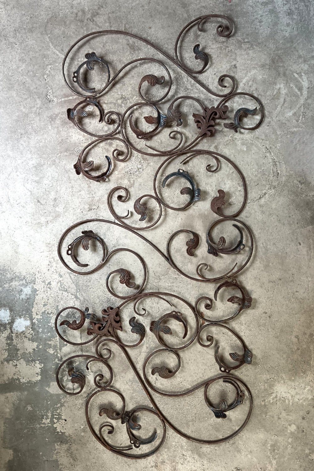 A pair of weathered wrought iron scroll panels featuring detailed acanthus leaves and a naturally oxidized brown finish.