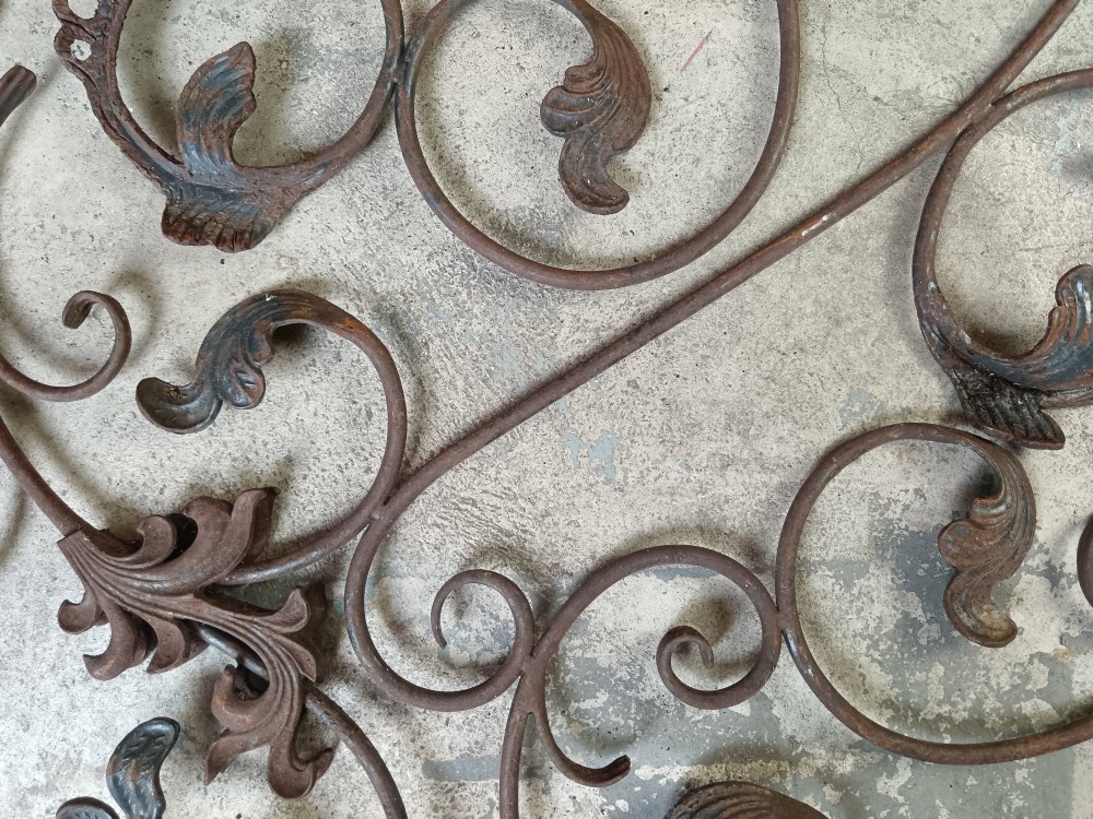 A pair of weathered wrought iron scroll panels featuring detailed acanthus leaves and a naturally oxidized brown finish. View VI