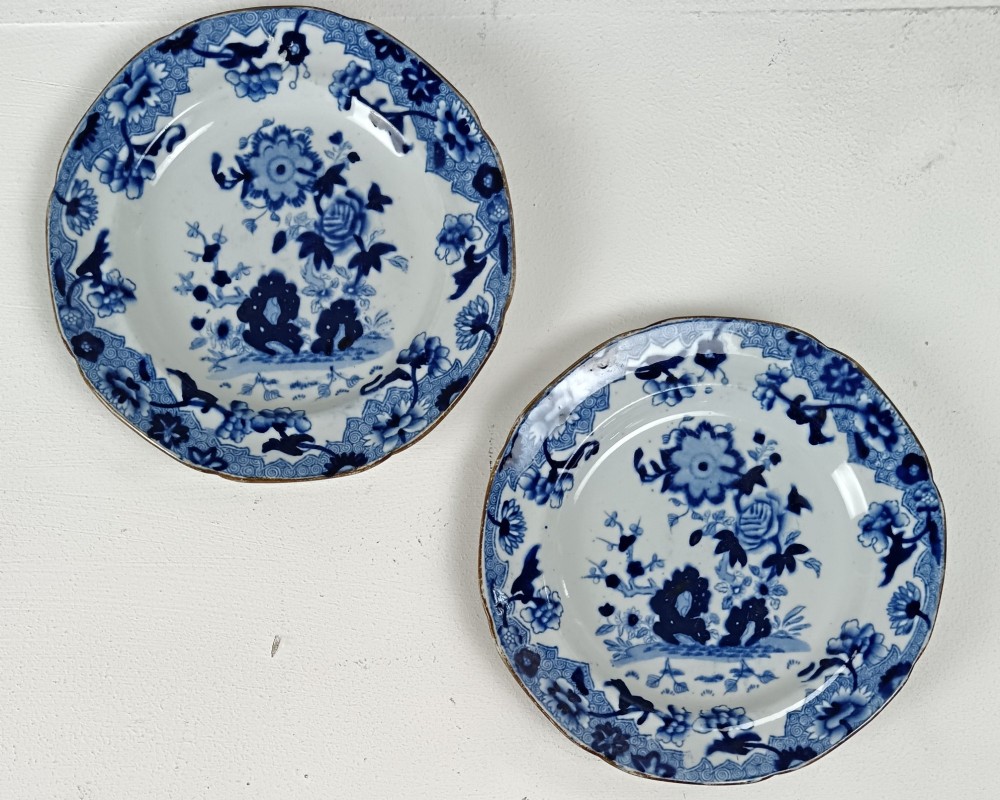 A pair of circular Georgian ceramic tea plates featuring blue and white floral underglaze decoration with scalloped edges.