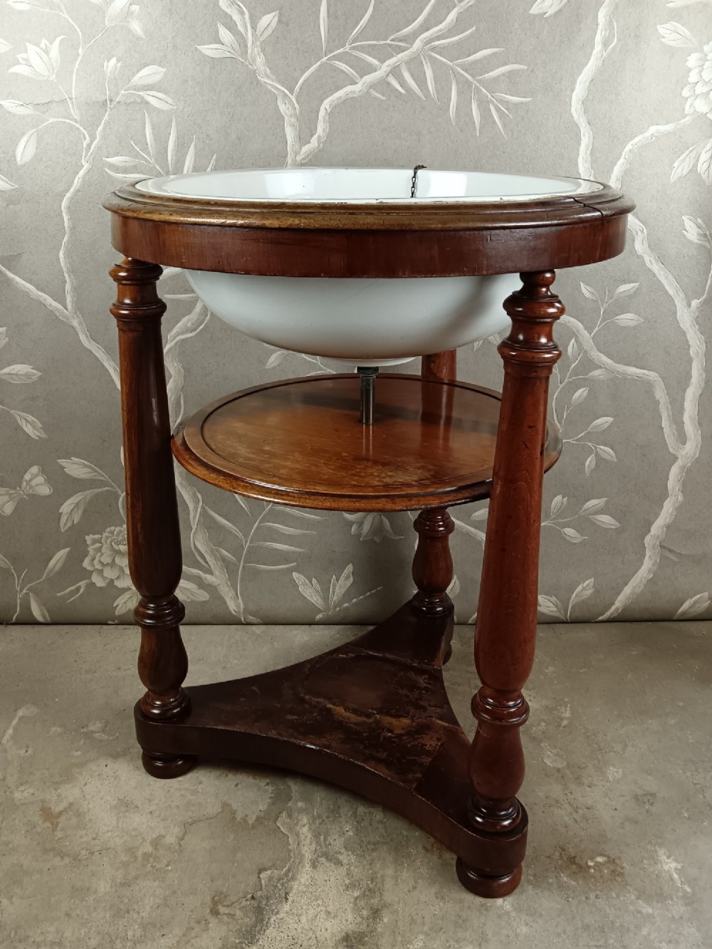 A 19th-century circular mahogany campaign washstand featuring three turned legs, a circular tier, a triangular platform base, and an inset white ceramic wash basin. View III