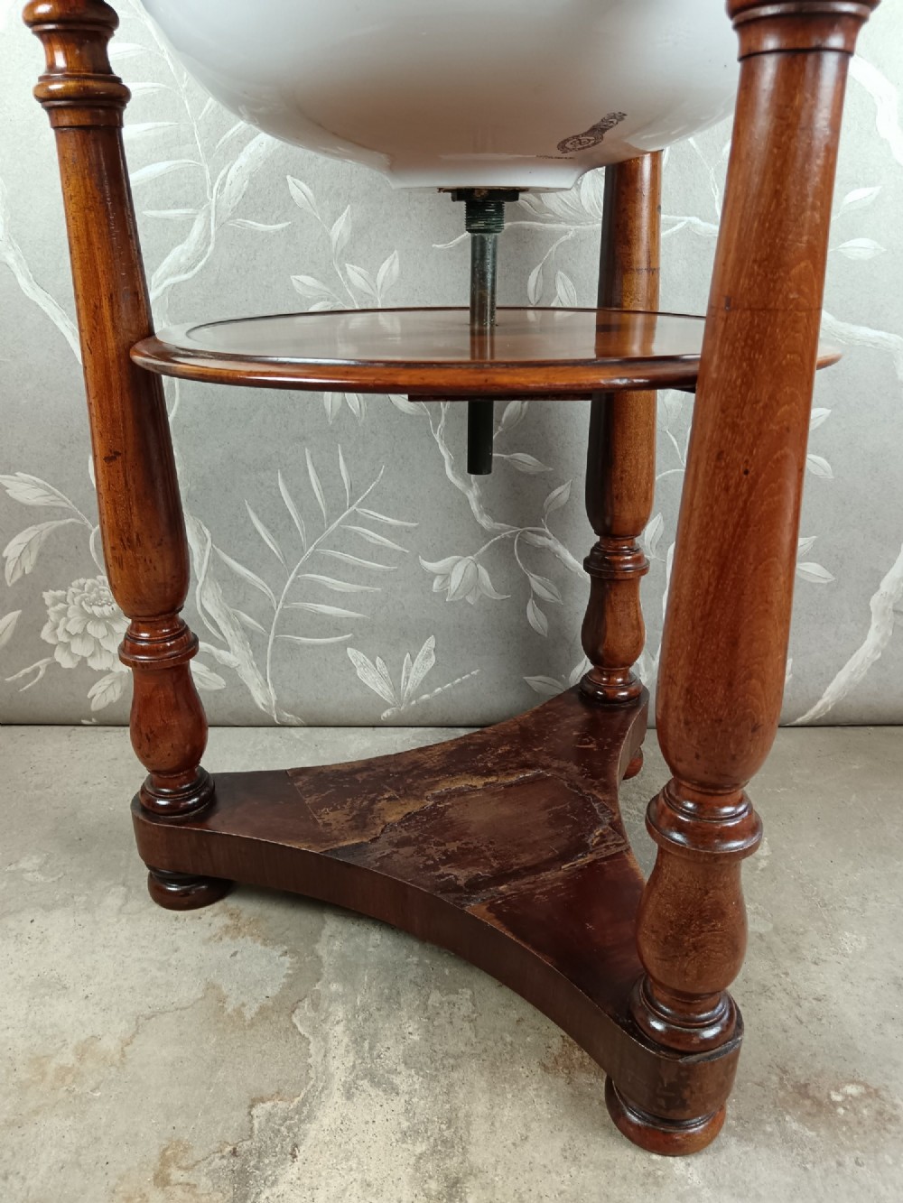 A 19th-century circular mahogany campaign washstand featuring three turned legs, a circular tier, a triangular platform base, and an inset white ceramic wash basin. View VI