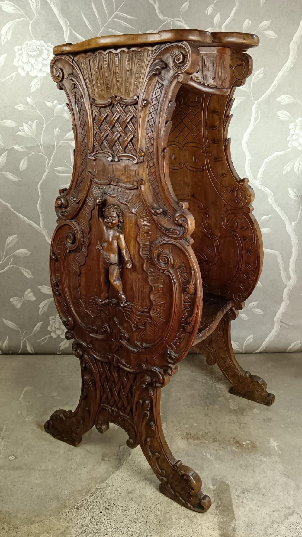 A 19th-century Italian carved walnut pedestal stand featuring a central relief carving of a cherub, acanthus scrollwork, and lattice detailing. View II
