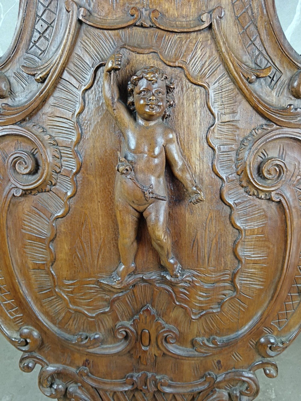 A 19th-century Italian carved walnut pedestal stand featuring a central relief carving of a cherub, acanthus scrollwork, and lattice detailing. View V