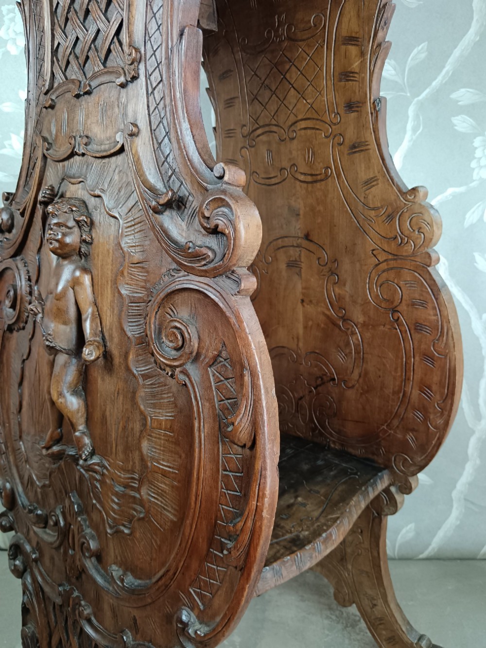 A 19th-century Italian carved walnut pedestal stand featuring a central relief carving of a cherub, acanthus scrollwork, and lattice detailing. View VI