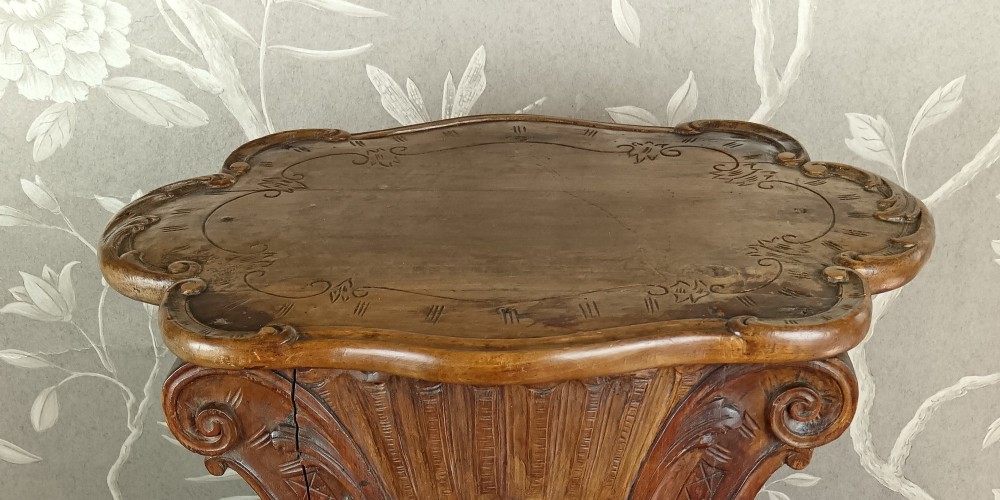 A 19th-century Italian carved walnut pedestal stand featuring a central relief carving of a cherub, acanthus scrollwork, and lattice detailing. View IX