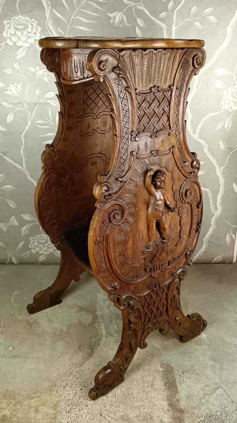 A 19th-century Italian carved walnut pedestal stand featuring a central relief carving of a cherub, acanthus scrollwork, and lattice detailing. View XII