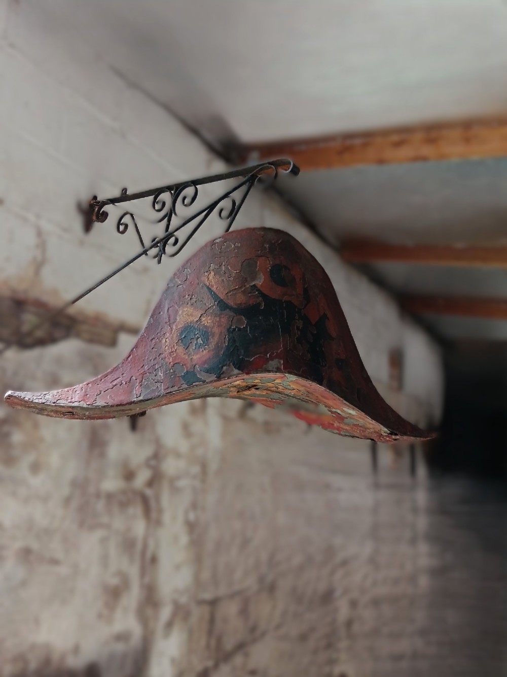 A nineteenth-century painted toleware trade sign shaped in the form of a military bicorn hat with gilt detailing. View V