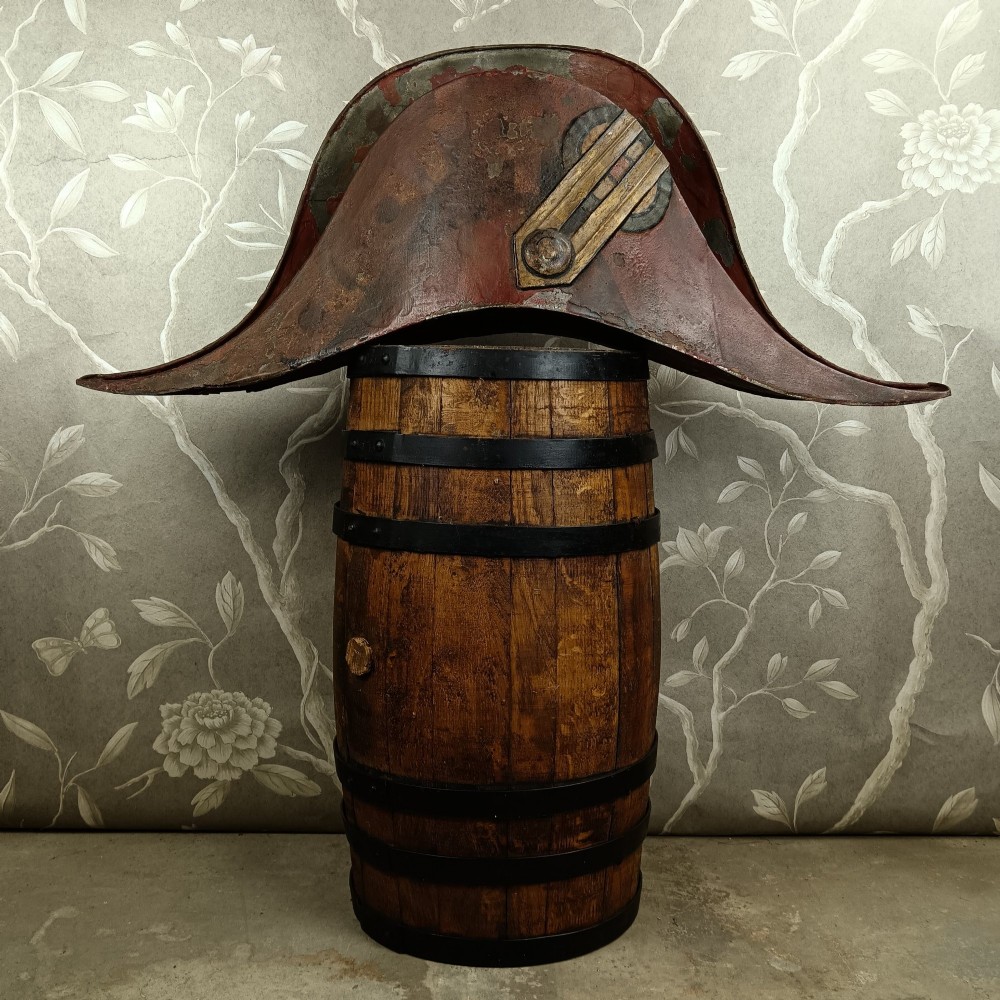 A nineteenth-century painted toleware trade sign shaped in the form of a military bicorn hat with gilt detailing. View II