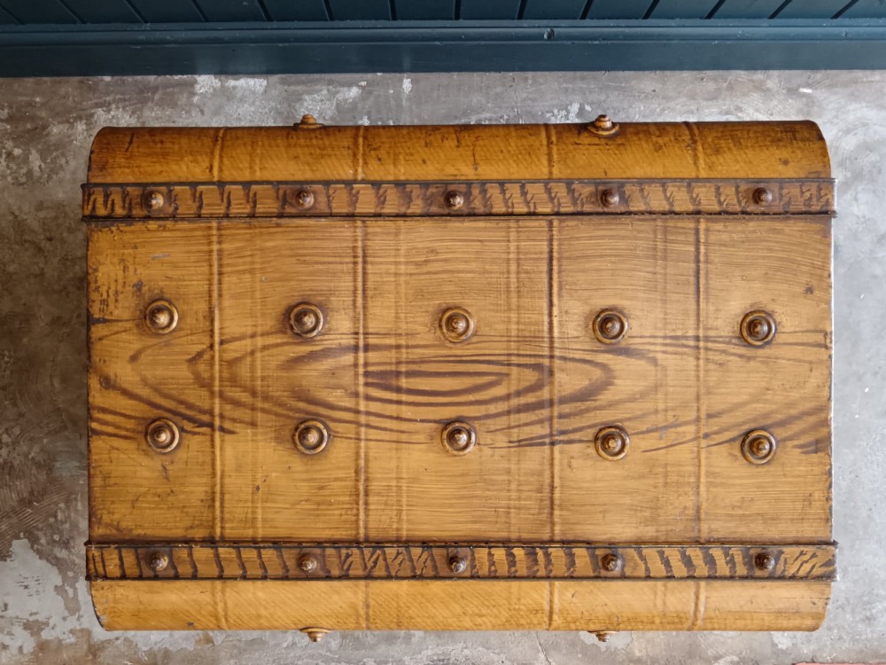 A late nineteenth-century metal steamer trunk featuring a hand-painted faux wood grain finish, dark metal banding, studs, and a central latch. View V