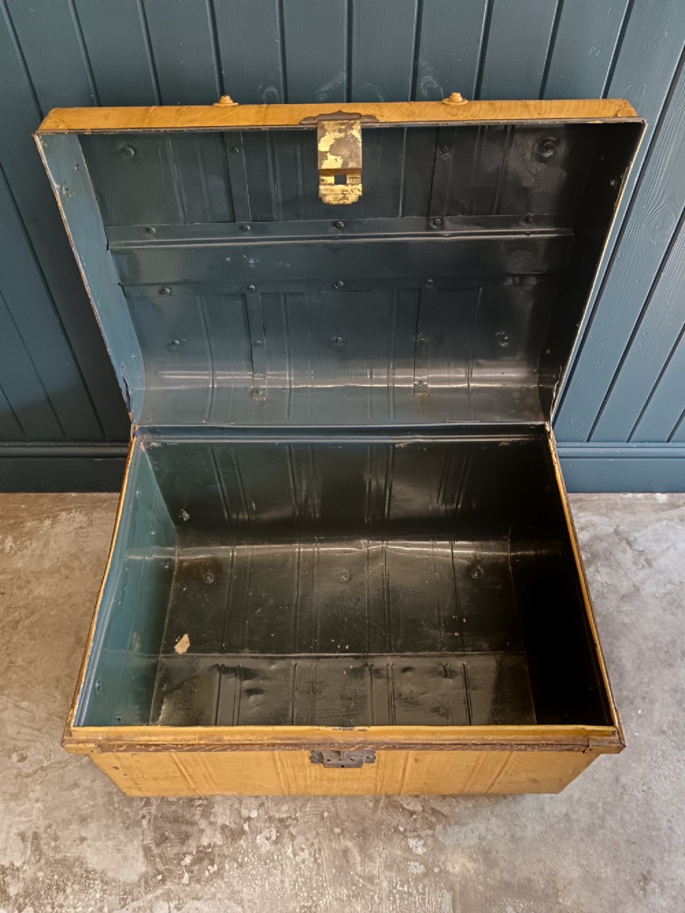 A late nineteenth-century metal steamer trunk featuring a hand-painted faux wood grain finish, dark metal banding, studs, and a central latch. View VII