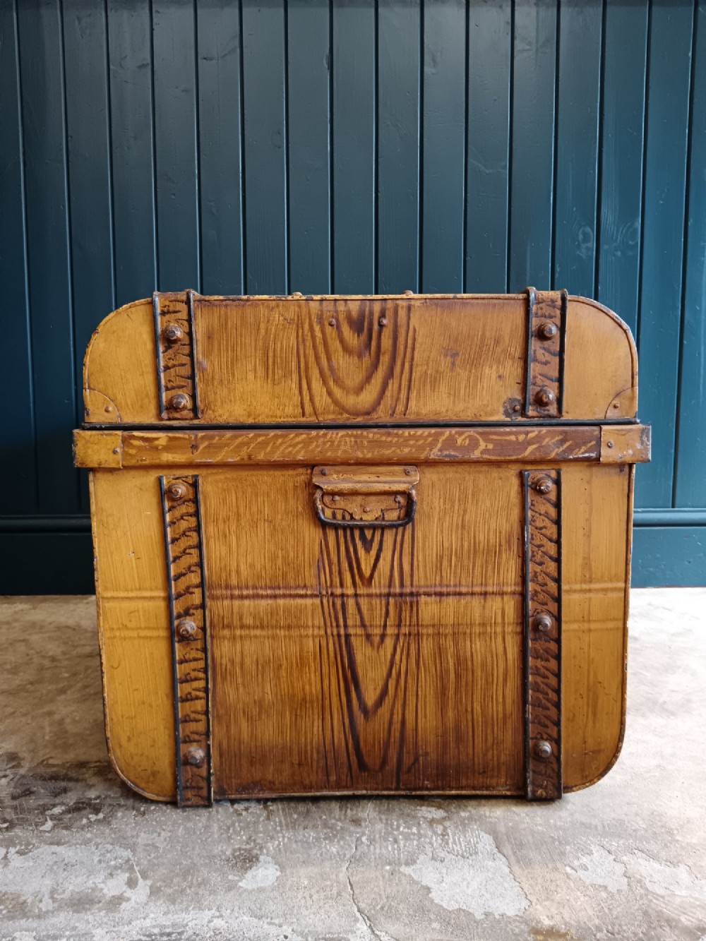 A late nineteenth-century metal steamer trunk featuring a hand-painted faux wood grain finish, dark metal banding, studs, and a central latch. View VIII