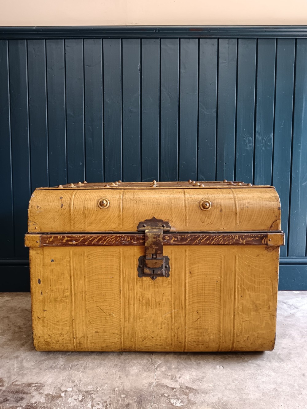 A late nineteenth-century metal steamer trunk featuring a hand-painted faux wood grain finish, dark metal banding, studs, and a central latch. View XI