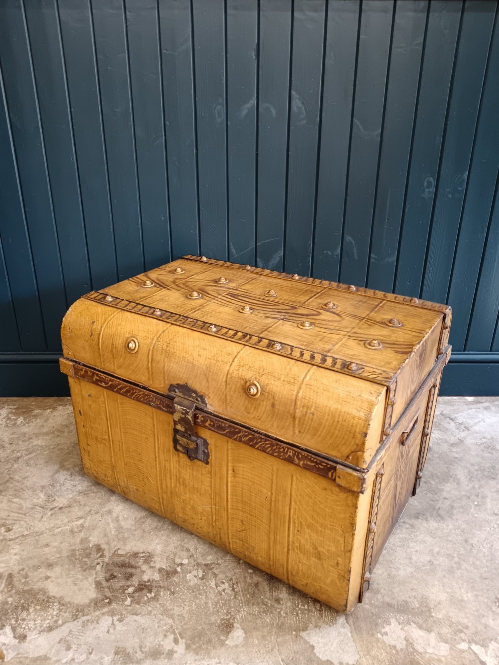 A late nineteenth-century metal steamer trunk featuring a hand-painted faux wood grain finish, dark metal banding, studs, and a central latch. View XII