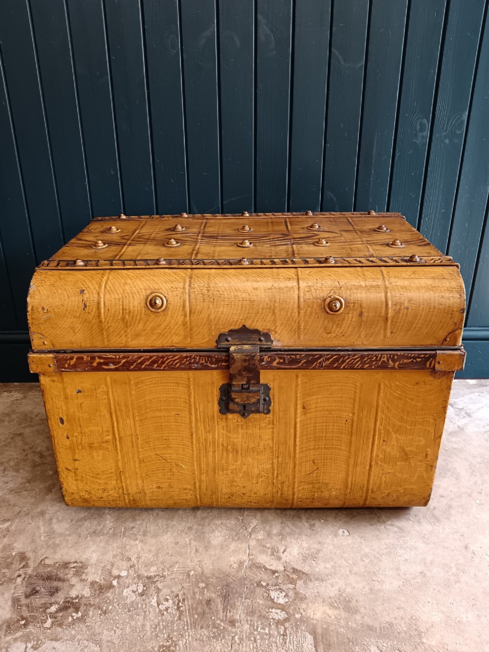A late nineteenth-century metal steamer trunk featuring a hand-painted faux wood grain finish, dark metal banding, studs, and a central latch. View XV