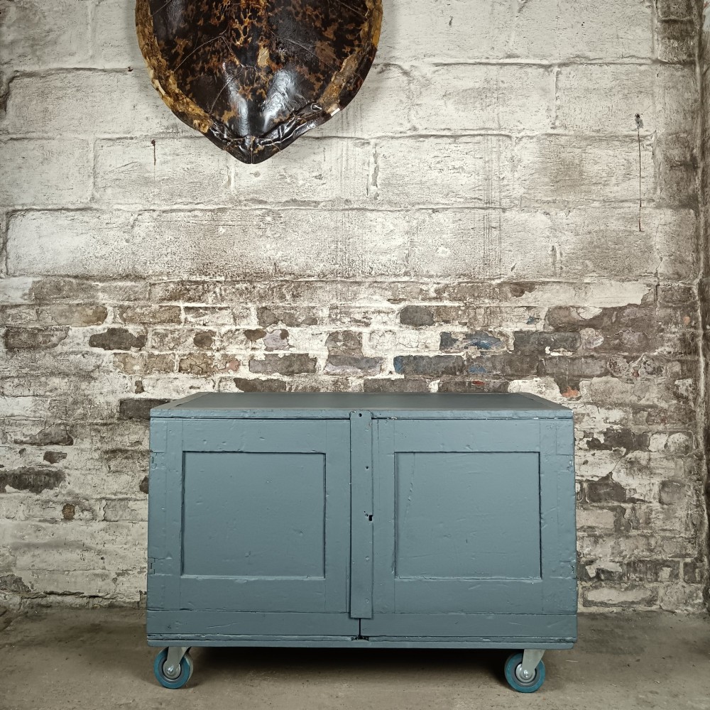 A 19th-century wooden military transport packing case featuring a slate grey painted finish and panelled front doors set on castors.