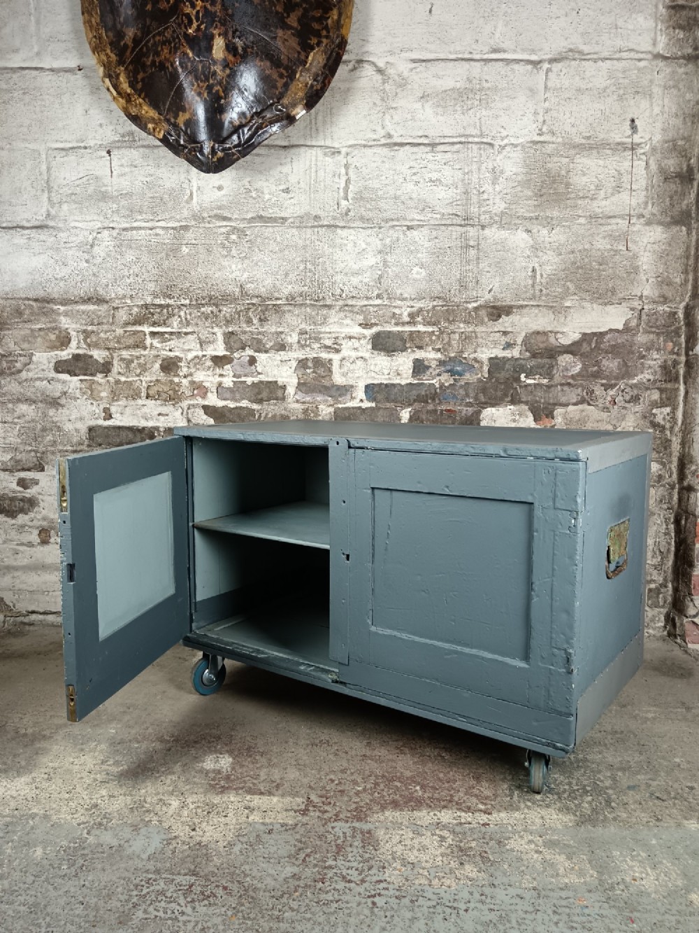 A 19th-century wooden military transport packing case featuring a slate grey painted finish and panelled front doors set on castors. View II