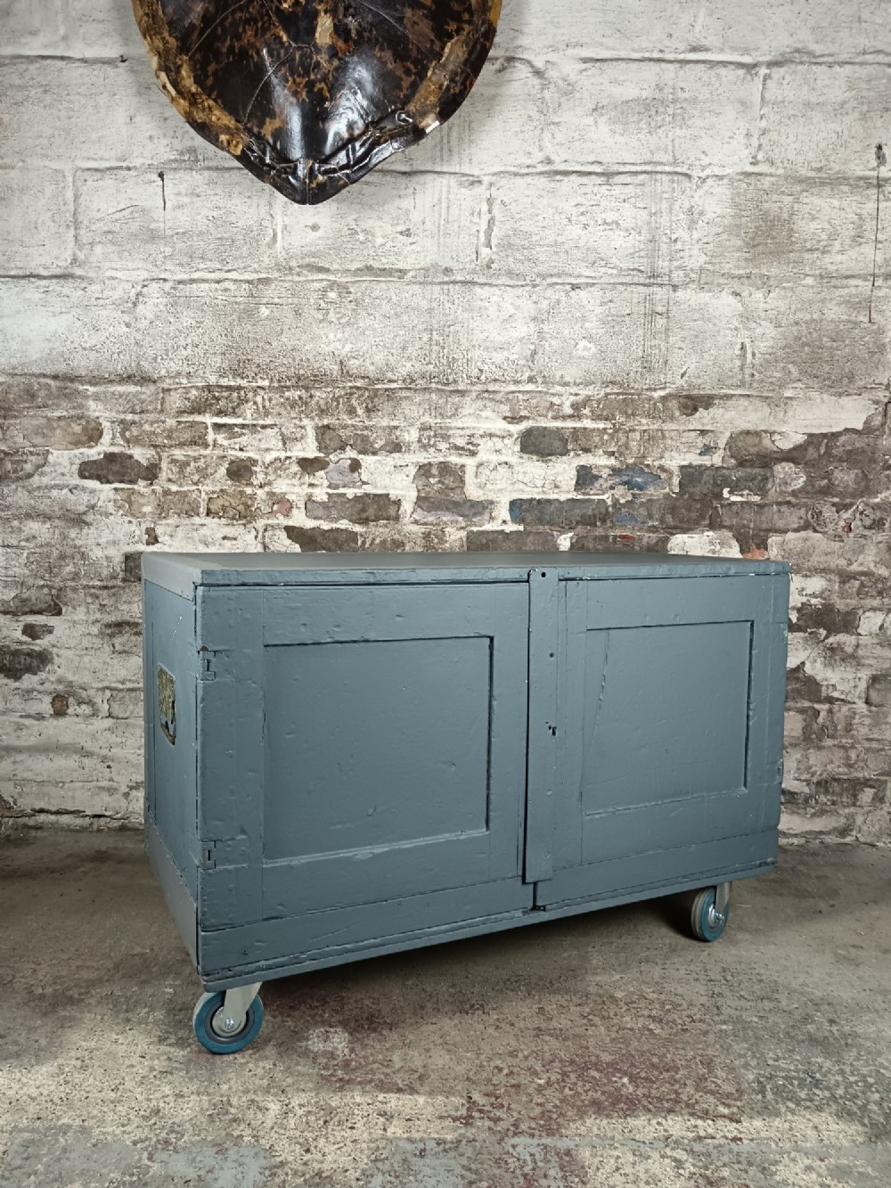A 19th-century wooden military transport packing case featuring a slate grey painted finish and panelled front doors set on castors. View V