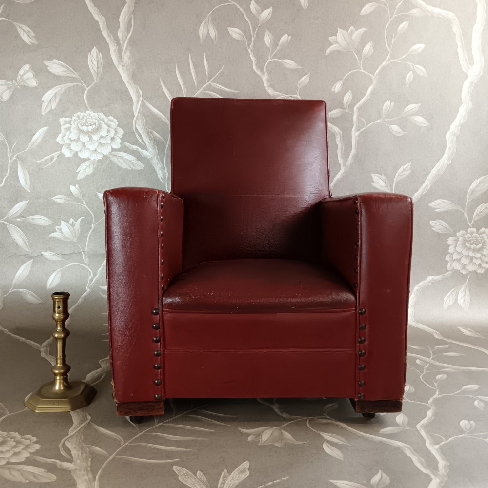 A child-sized 1930s Art Deco club chair upholstered in oxblood red leather with studded trim along the arms. View II
