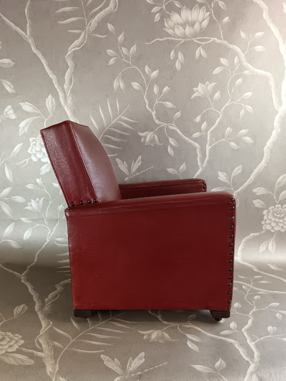 A child-sized 1930s Art Deco club chair upholstered in oxblood red leather with studded trim along the arms. View III
