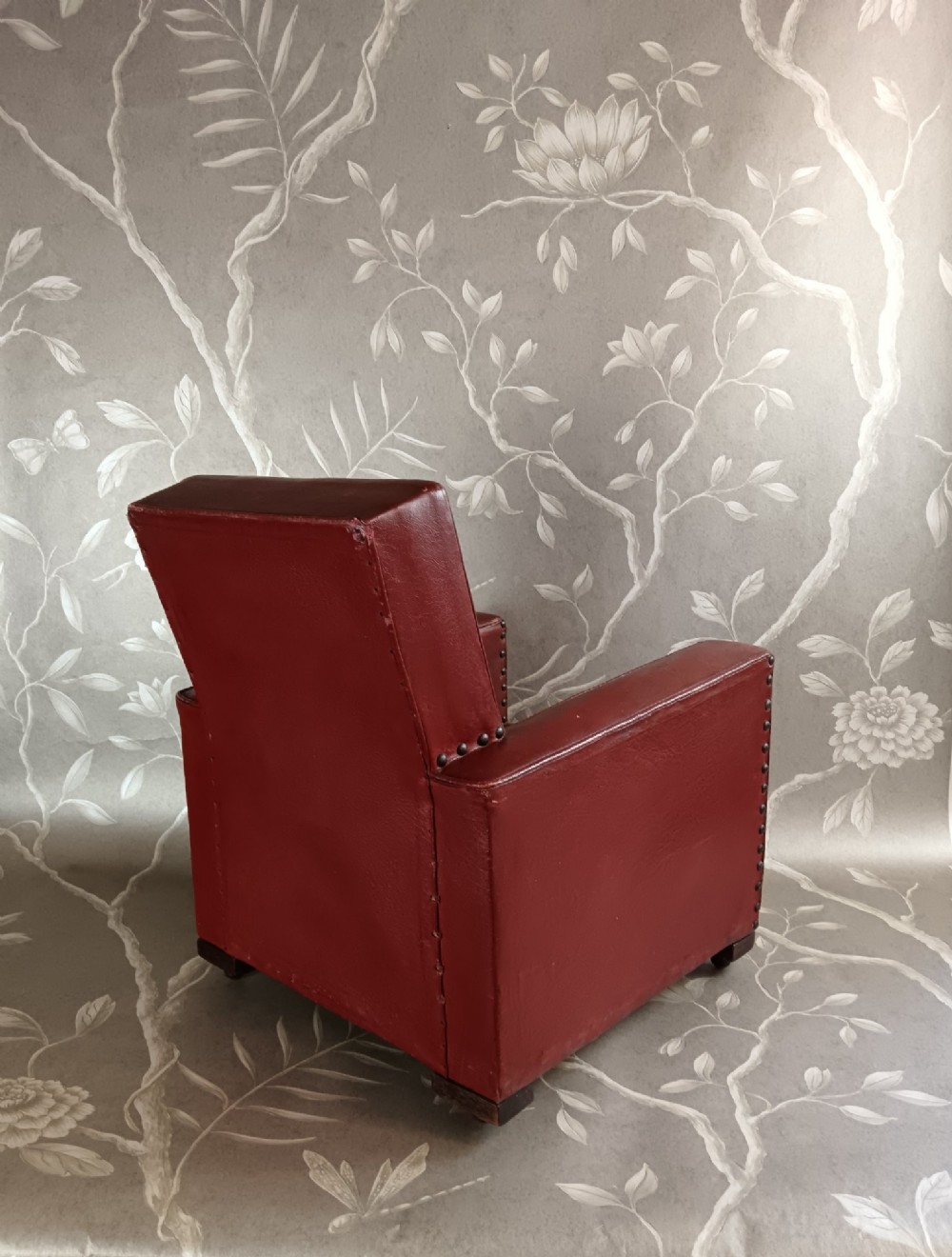 A child-sized 1930s Art Deco club chair upholstered in oxblood red leather with studded trim along the arms. View IV