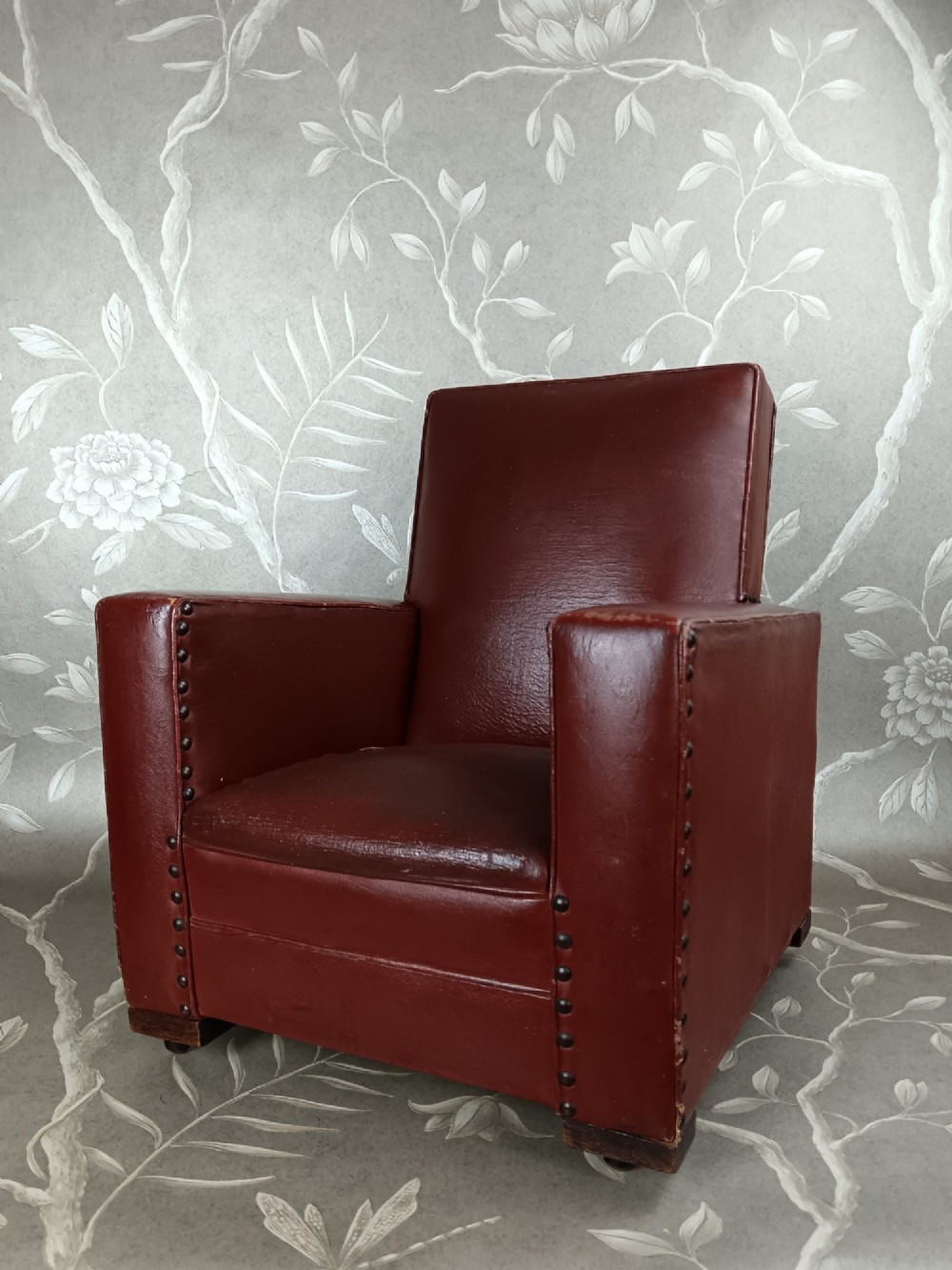 A child-sized 1930s Art Deco club chair upholstered in oxblood red leather with studded trim along the arms. View VIII