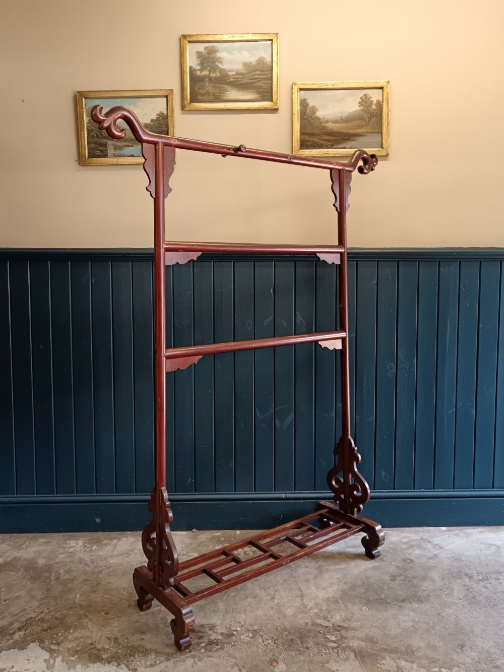 A late 19th-century Chinese red lacquered wooden robe stand with carved scroll terminals, horizontal crossbars, and a lower latticework base. View II
