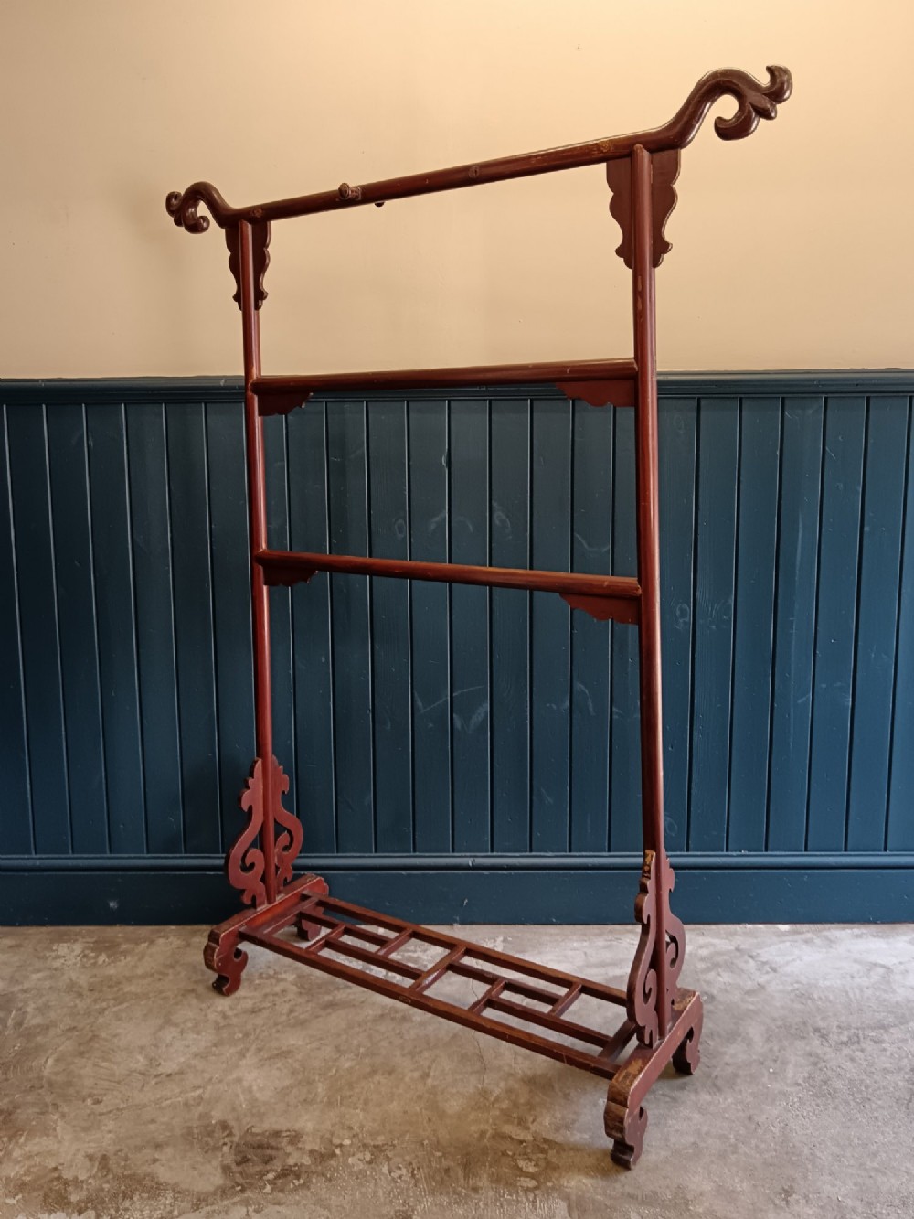 A late 19th-century Chinese red lacquered wooden robe stand with carved scroll terminals, horizontal crossbars, and a lower latticework base. View III