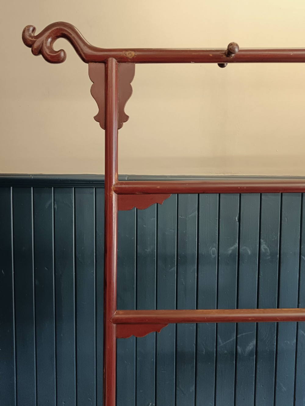 A late 19th-century Chinese red lacquered wooden robe stand with carved scroll terminals, horizontal crossbars, and a lower latticework base. View IV