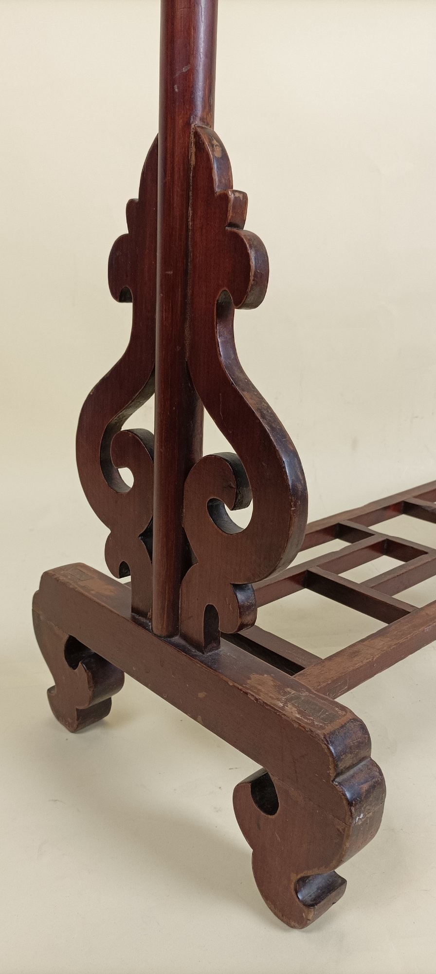 A late 19th-century Chinese red lacquered wooden robe stand with carved scroll terminals, horizontal crossbars, and a lower latticework base. View V