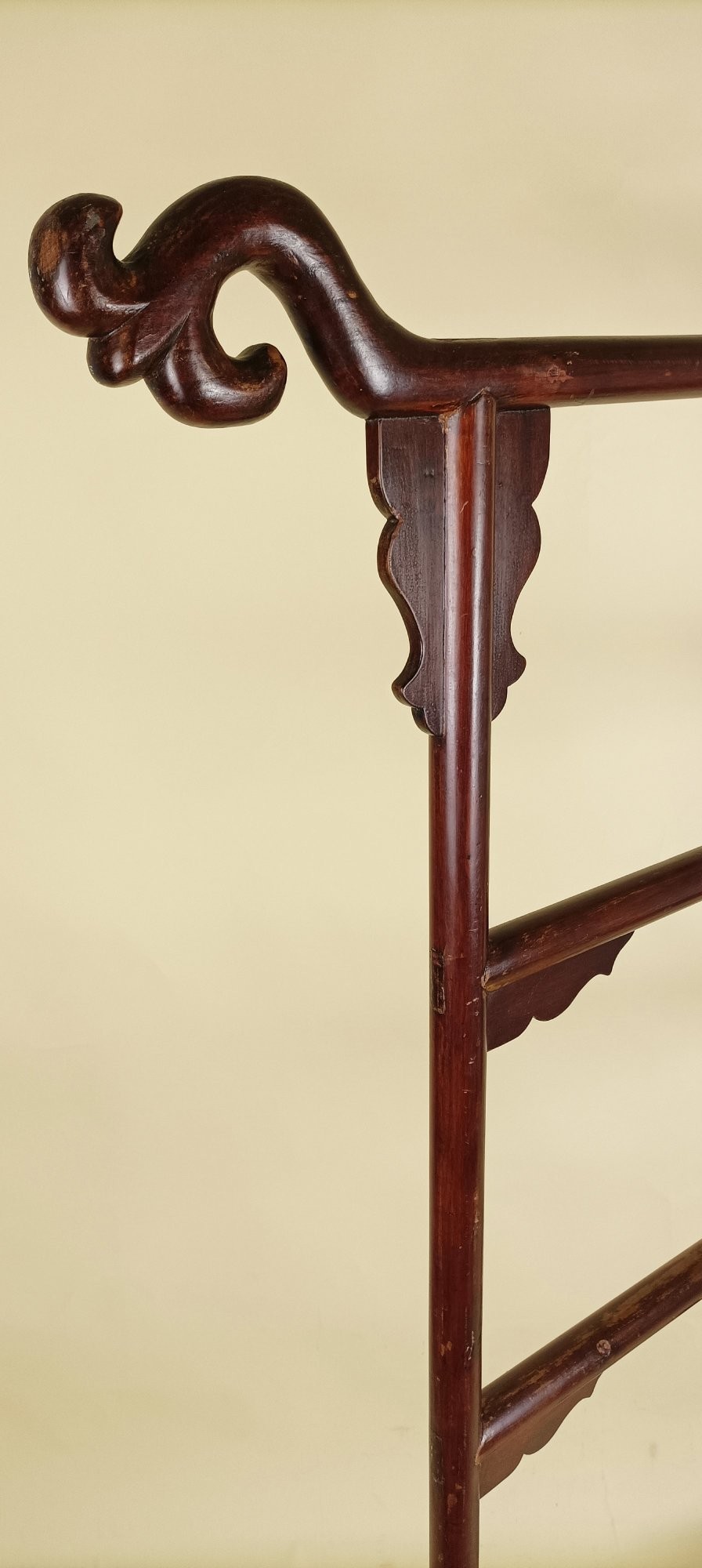A late 19th-century Chinese red lacquered wooden robe stand with carved scroll terminals, horizontal crossbars, and a lower latticework base. View VII