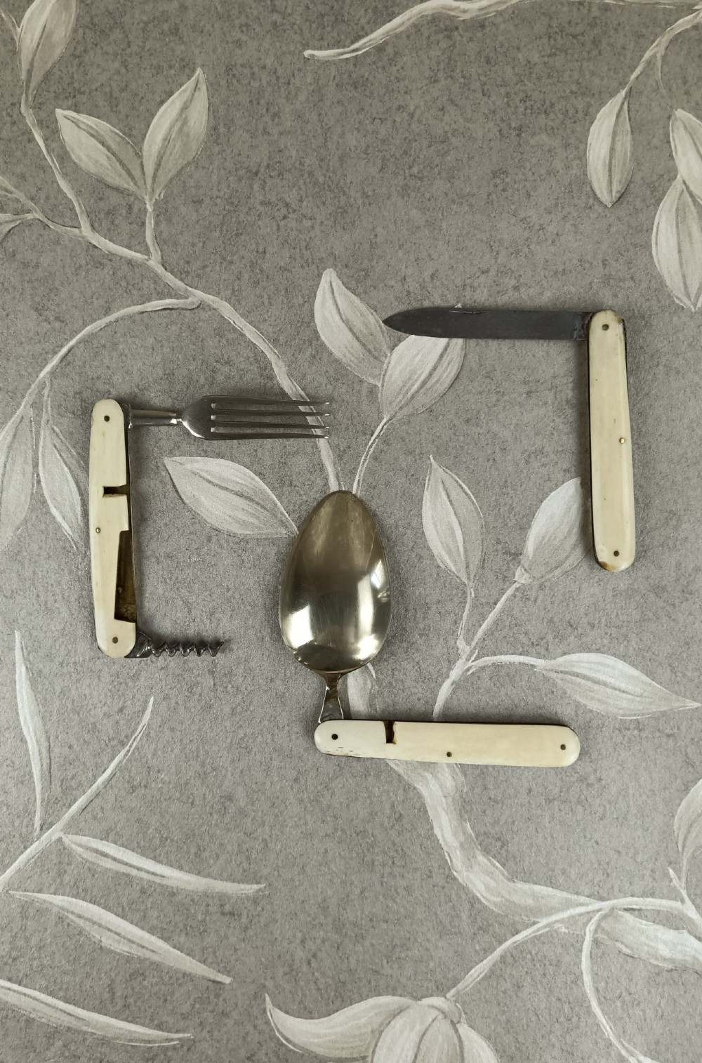 A Victorian folding campaign cutlery set featuring silver-plated utensils with light-coloured handles, a clear glass beaker, and a fitted dark red morocco leather carrying case. View VIII