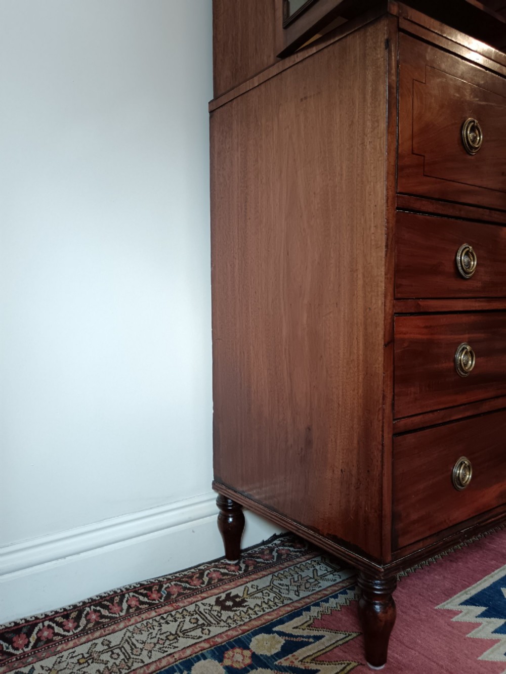 A Regency mahogany secretaire cabinet featuring a triangular pediment top, glazed upper doors, a fall-front desk section, and three drawers below on turned feet. View VII