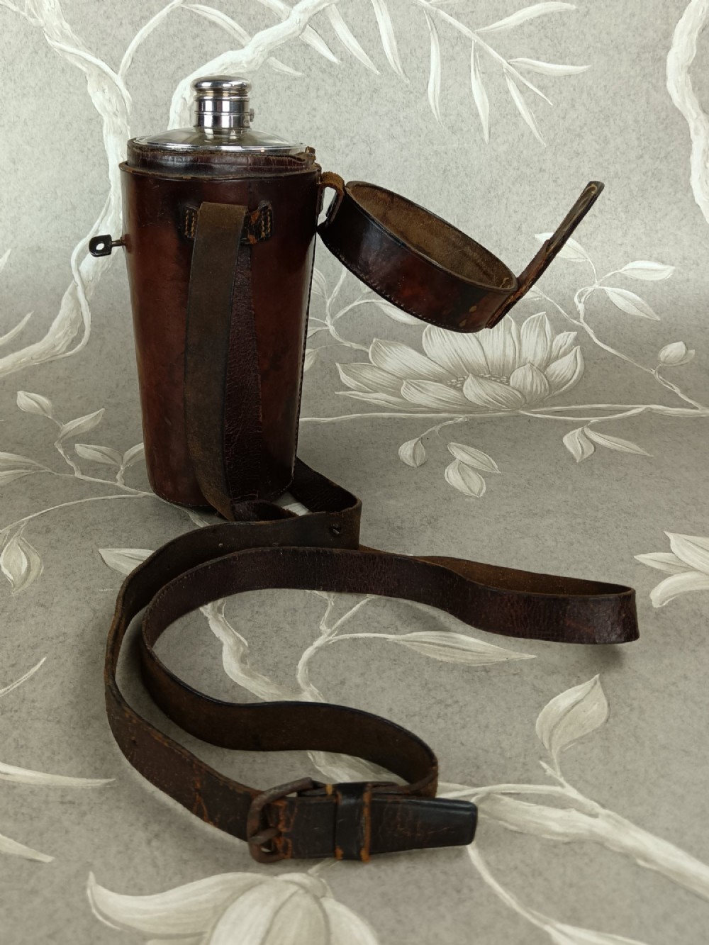 A Victorian leather campaign case with a shoulder strap alongside a glass flask and two silver-plated nesting beaker cups. View II