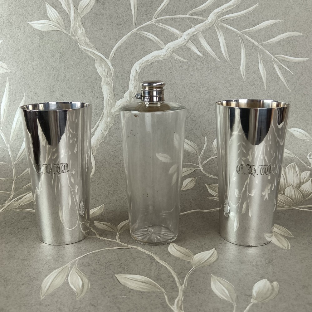 A Victorian leather campaign case with a shoulder strap alongside a glass flask and two silver-plated nesting beaker cups. View VI